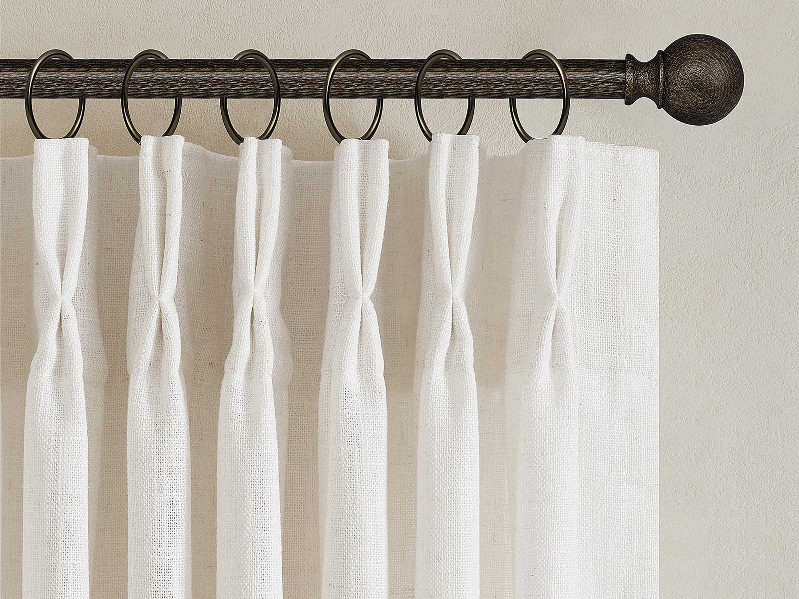 Close-up of pinch pleat curtain header showing sewn pleats and curtain hooks