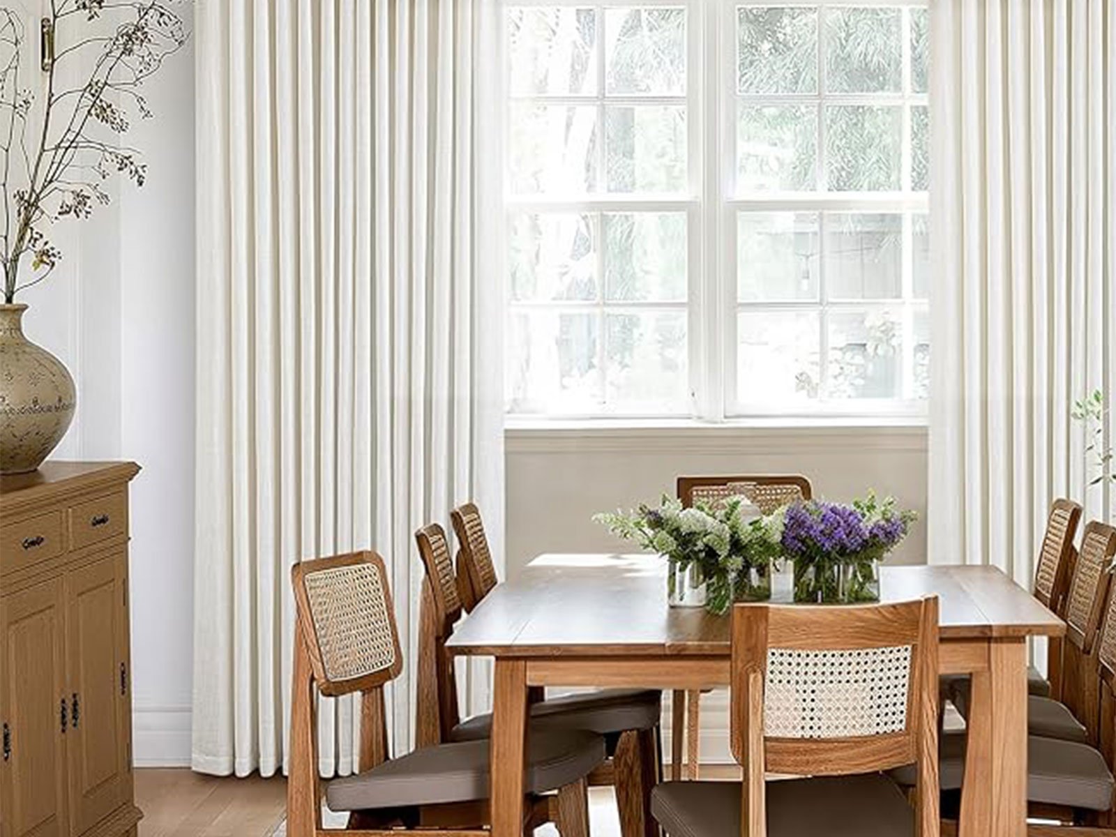 Sheer pinch pleat curtains layered with drapery in a bright dining room